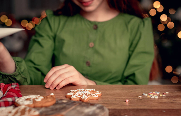 Girl in festive apron decorating gingerbread - Zdjęcie, obraz