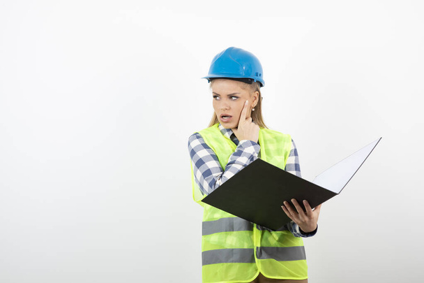 Portrait of blonde female engineer in hardhat reading notes. High quality photo - Photo, image