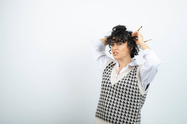 Foto de jovem com coque bagunçado fazendo seu cabelo com escovas. Foto de alta qualidade - Foto, Imagem