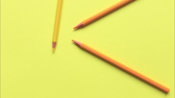 De beweging van gekleurde potloden op een gele achtergrond. - Video