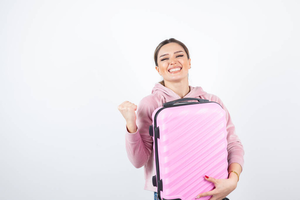 Image of attractive woman in pink hoodie holding suitcase. High quality photo - Photo, Image