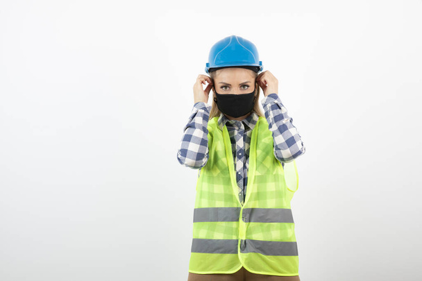 Photo of construction worker in hardhat wearing medical mask for covid. High quality photo - Fotografie, Obrázek