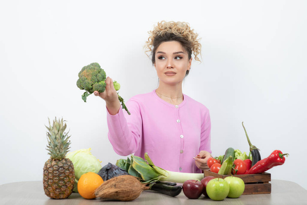 mooie vrouw poseren met diverse groenten en fruit op tafel - Foto, afbeelding