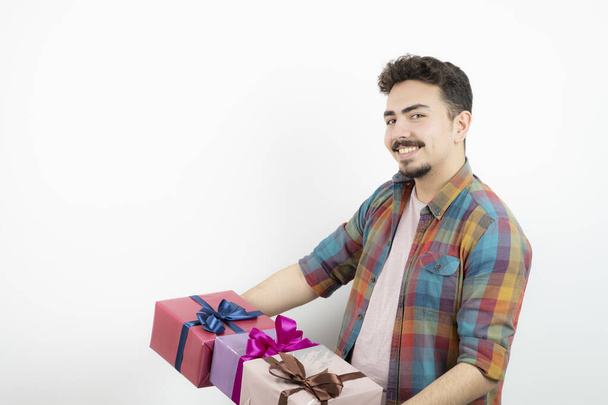 Portrait d'un homme séduisant tenant des boîtes cadeaux et regardant la caméra. Photo de haute qualité - Photo, image