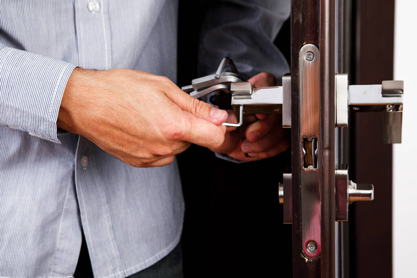 man repairing the doorknob. closeup of worker's hands installing new door locker - Foto, Bild