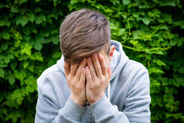 Sad Teenager is Crying on the Green Leaves Background outdoor - 写真・画像