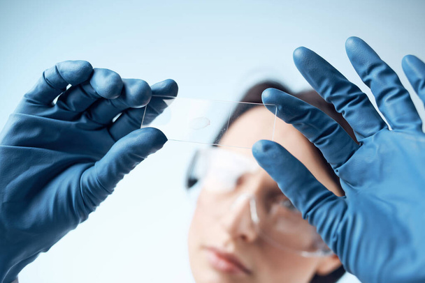 vrouw met blauwe handschoenen test onderzoek analyse diagnostiek - Foto, afbeelding