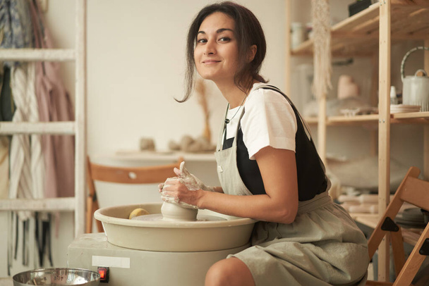 Smiling craftswoman working at pottery wheel - Фото, зображення
