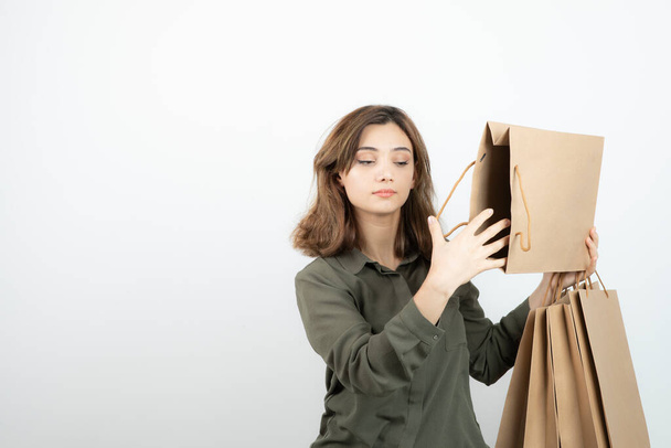 Портрет молодой женщины, держащей бумажные пакеты и стоящей. Высокое качество фото - Фото, изображение