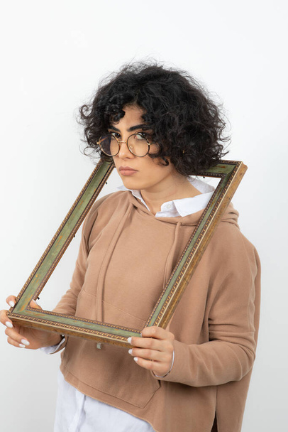 frisé brunette jeune femme drôle posant avec vide cadre photo - Photo, image