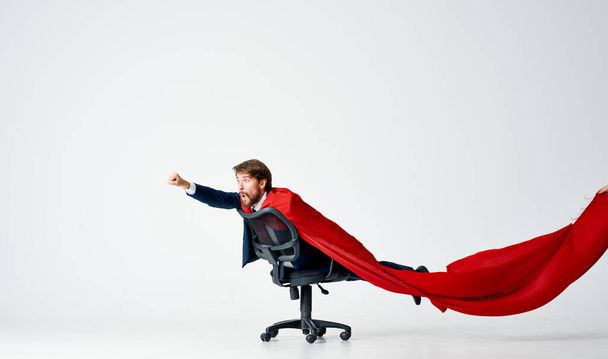 mies punaisessa puvussa ratsastaa tuolissa supersankareita - Valokuva, kuva