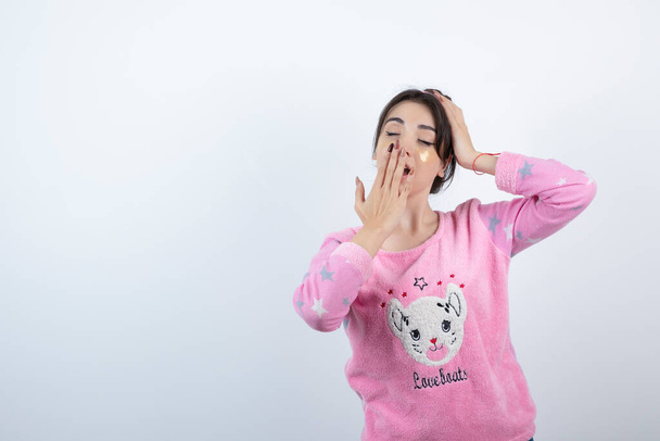 Foto de una joven en pijama con parches en los ojos bostezando. Foto de alta calidad - Foto, imagen