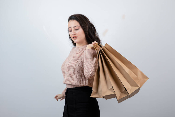 Retrato hermosa mujer en suéter sosteniendo bolsas de paquetes con compras después de comprar. Foto de alta calidad - Foto, imagen