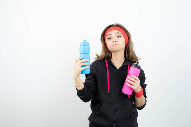 Zdjęcie młodej sportowej dziewczyny trzymającej różową butelkę wody. Wysokiej jakości zdjęcie - Zdjęcie, obraz