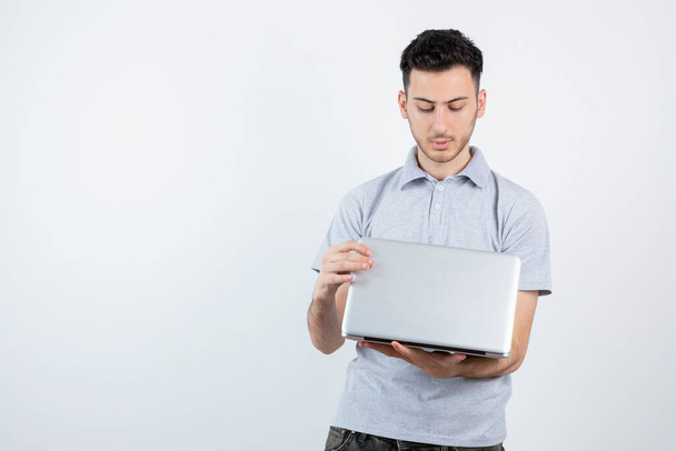 Portrait de jeune homme tenant un ordinateur portable au-dessus d'un mur blanc. Photo de haute qualité - Photo, image