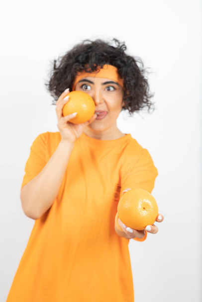 woman in orange t-shirt posing with oranges - Photo, Image