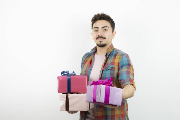 Retrato de um homem atraente dando caixas de presente e olhando para a câmera. Foto de alta qualidade - Foto, Imagem