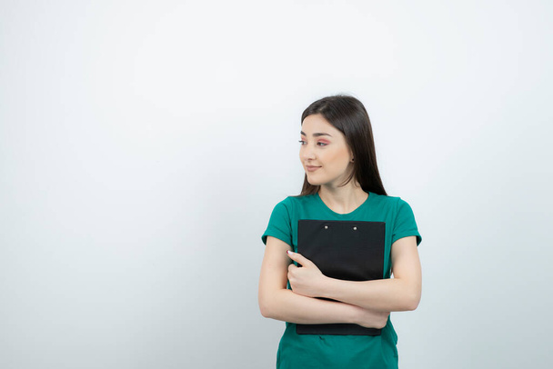 Photo of pretty girl in blue t-shirt with clipboard standing arms crossed. High quality photo - Foto, immagini