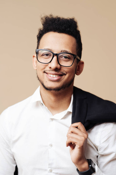 Afro bel ragazzo in camicia bianca e occhiali in posa su sfondo beige - Foto, immagini