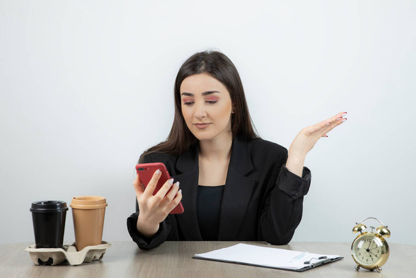 Portrait of businesswoman sitting at her workplace with her mobile phone .High quality photo - Фото, зображення