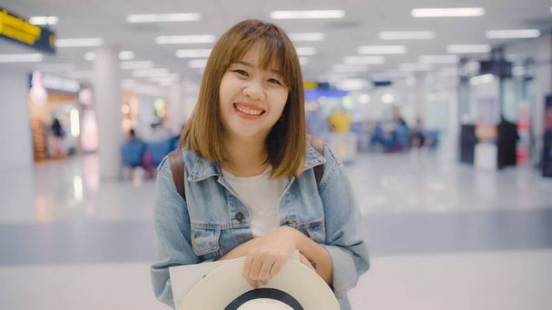 Heureuse femme asiatique souriant à la caméra tout en restant au terminal de l'aéroport international, touriste féminine prête à voyager en vacances. Lifestyle femmes joyeuses vacances dans le concept de l'aéroport
. - Photo, image