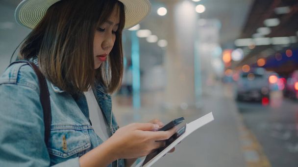 Onnellinen aasialainen nainen, joka käyttää ja tarkistaa älypuhelimensa terminaalissa odottaessaan lentoa lähtöportilla kansainvälisellä lentokentällä. Naiset onnellinen airport käsite
. - Valokuva, kuva