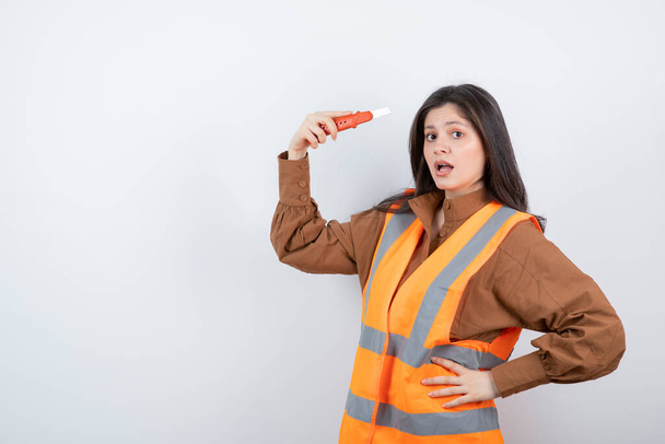 Elinde maket bıçağıyla turuncu yelek giyen kadın mühendis. Yüksek kalite fotoğraf - Fotoğraf, Görsel
