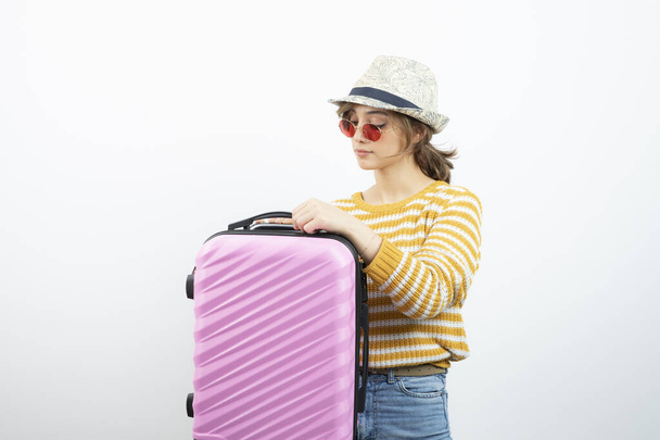 Picture of a young female tourist in hat holding pink travel suitcase . High quality photo - Photo, Image