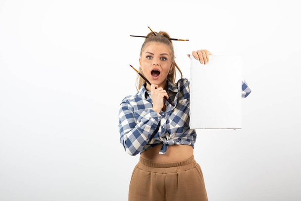 Portrait of female artist with blank canvas and paintbrush posing. High quality photo - 写真・画像