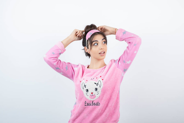 Photo of a cute girl model in pajama standing and correcting her hair bun . High quality photo - Photo, Image