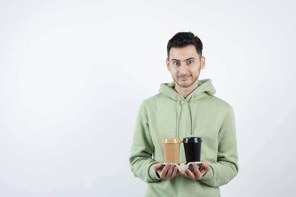 Young man in sweatshirt with takeaway coffee cups posing. High quality photo - Foto, Imagem