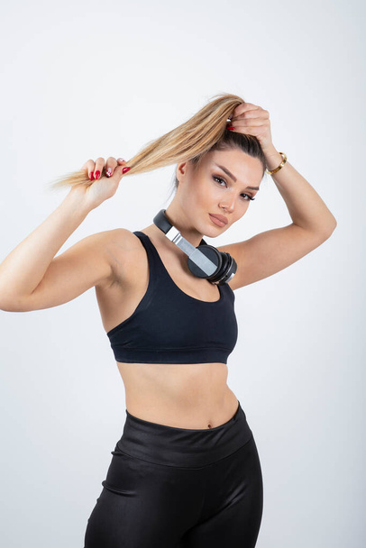 красива молода жінка в спортивному одязі позує з навушниками на шиї
 - Фото, зображення