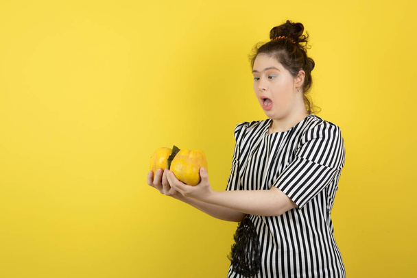 Aranyos Down-szindrómás lány portréja érett birsalma gyümölcsökkel a kezében. Kiváló minőségű fénykép - Fotó, kép