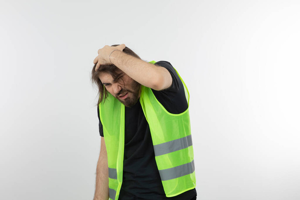 Foto de un joven trabajador industrial con chaleco verde protegiendo su cabeza. Foto de alta calidad - Foto, imagen