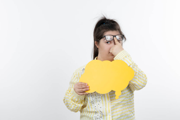 девушка с синдромом Дауна позирует с желтым пузырём речи вырезать бумагу - Фото, изображение
