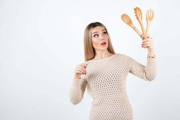 Foto de mujer joven atractiva de pie y sosteniendo herramientas de cocina. Foto de alta calidad - Foto, imagen