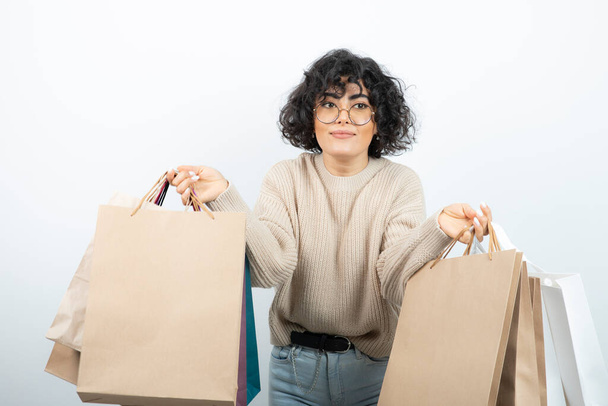 Image of brunette woman in glasses holding bunch of shopping bags. High quality photo - Foto, afbeelding