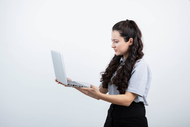 Портрет молодої брюнетки, яка тримає ноутбук на білому тлі. Високоякісна фотографія
 - Фото, зображення