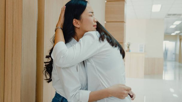 Молодая азиатка обнимает свою мать и плачет после того, как получает плохие новости от врача о ее отца в больнице, женщины плачут ждать хирургического оператора чувствовать себя грустно и безнадежно перед приемным отделением. - Фото, изображение