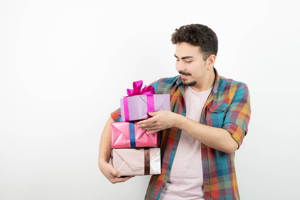 Portrait of an attractive man holding present boxes over a white wall . High quality photo - Foto, Imagem
