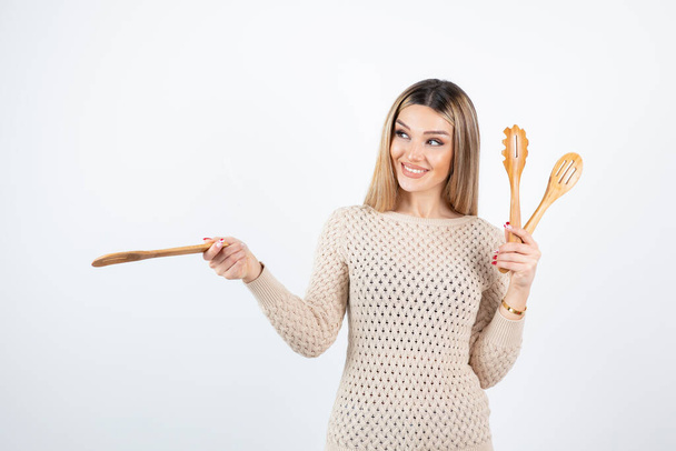 Photo d'une jolie jeune femme debout et tenant des outils de cuisine. Photo de haute qualité - Photo, image