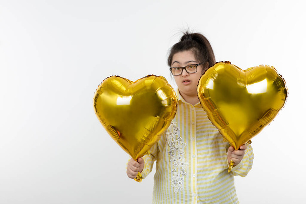 dziewczyna z zespołem Downa pozowanie ze złotym sercem balony - Zdjęcie, obraz