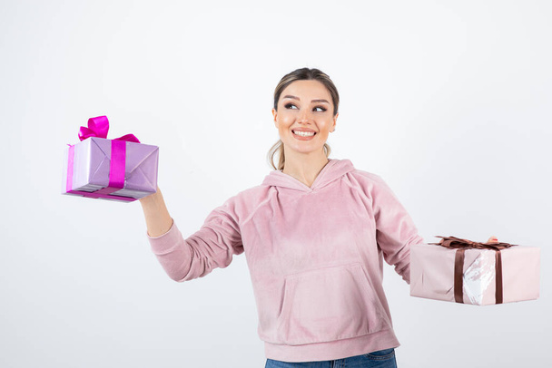 Молода приваблива жіноча модель з подарунковими коробками, що стоять над білим. Високоякісна фотографія
 - Фото, зображення