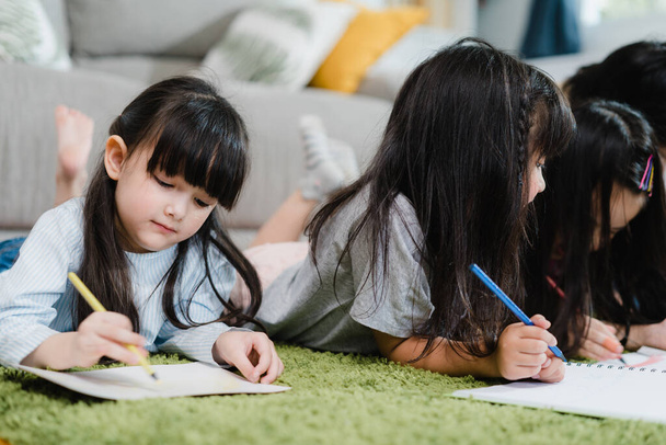 Eine Gruppe von Kindern zeichnet im Klassenzimmer, multiethnische Jungen und Mädchen freuen sich über lustiges Lernen und spielen Malen auf Papier in der Grundschule. Kinder zeichnen und malen im Schulkonzept. - Foto, Bild