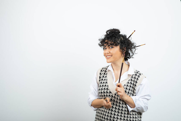 Γυναίκα καλλιτέχνης στέκεται και ποζάρει με βούρτσα στα μαλλιά της κουλούρι. Υψηλής ποιότητας φωτογραφία - Φωτογραφία, εικόνα
