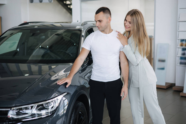 Portret pięknej młodej pary szczęśliwy po zakupie nowego samochodu z salonu samochodowego. Kobieta hus jej mężczyzna i zadowolony - Zdjęcie, obraz