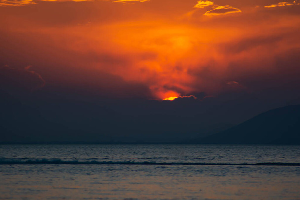 Φανταστικό ηλιοβασίλεμα πάνω από τη θάλασσα. Τεράστιος χρυσός ήλιος πάνω από τη θάλασσα. Οι ακτίνες του ήλιου αντανακλώνται στα νερά της θάλασσας. Πορτοκαλί ουρανό και ήλιος. Όμορφο τοπίο με θάλασσα και ήλιο. Πορτοκαλί θέα ηλιοβασίλεμα - Φωτογραφία, εικόνα