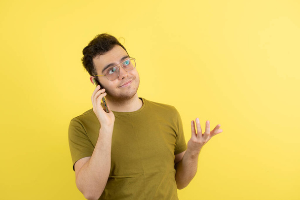 portrét chlapa mluvící na mobilním telefonu na žlutém pozadí. - Fotografie, Obrázek