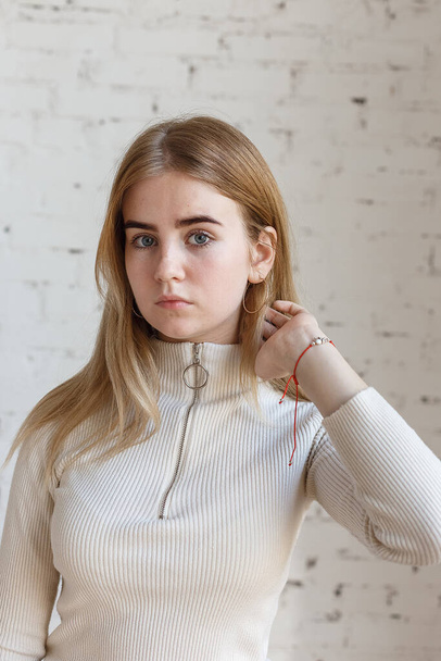 closeup portrait of thoughtful teen model with blue eyes wearing white sweater - Fotó, kép