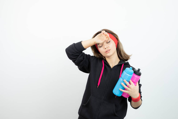 Φωτογραφία ενός νεαρού αθλητικού κοριτσιού που κρατάει ροζ μπουκάλι νερό. Υψηλής ποιότητας φωτογραφία - Φωτογραφία, εικόνα